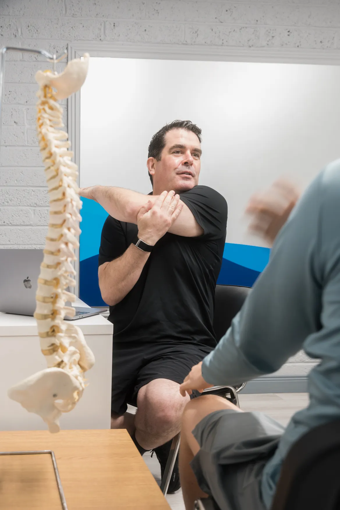 A physiotherapist showing a patient a shoulder stretch to do at home