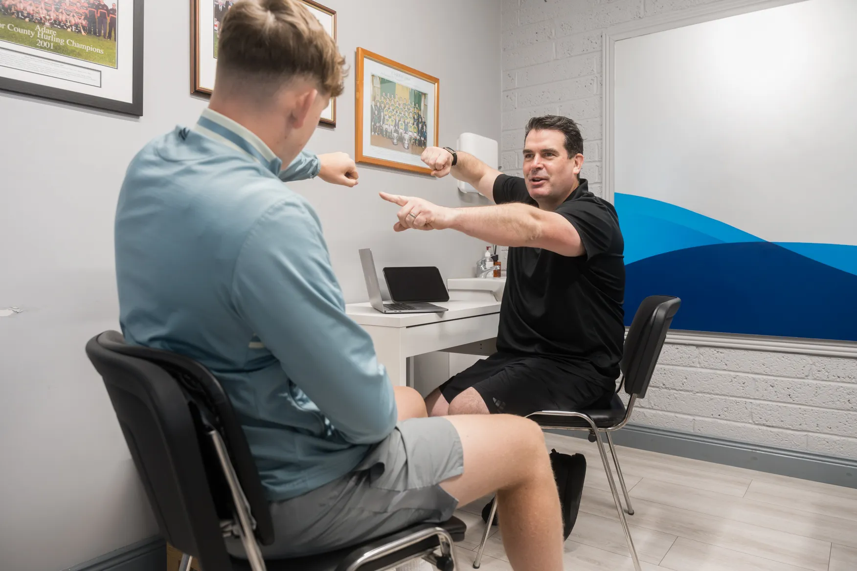 Physiotherapist talking with a young athlete in front of team photos