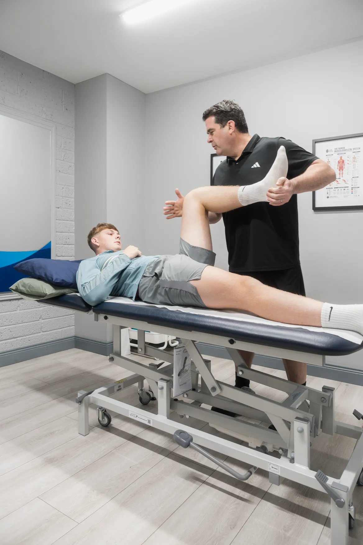 Physiotherapist assessing a patient's knee and hip on the treatment plinth
