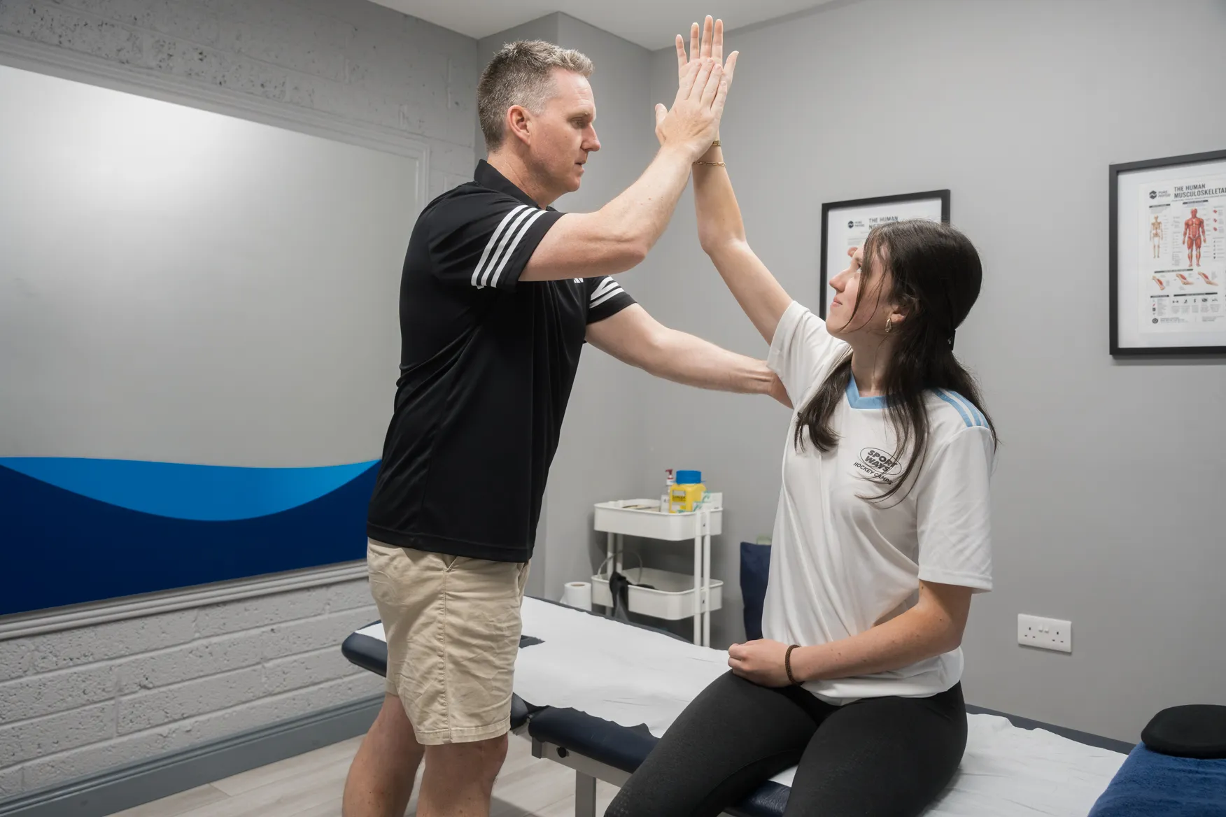 Physiotherapist assessing a patient's shoulder strength