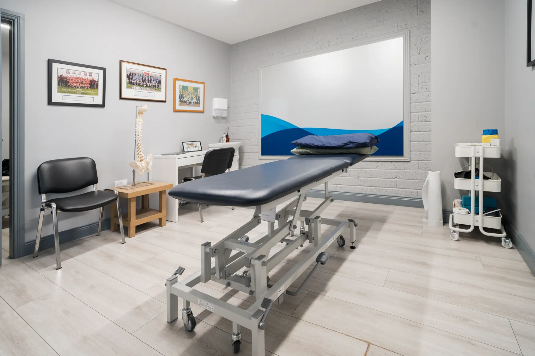 The Pure Physio treatment room with a treatment plinth and the blue wave wall graphic