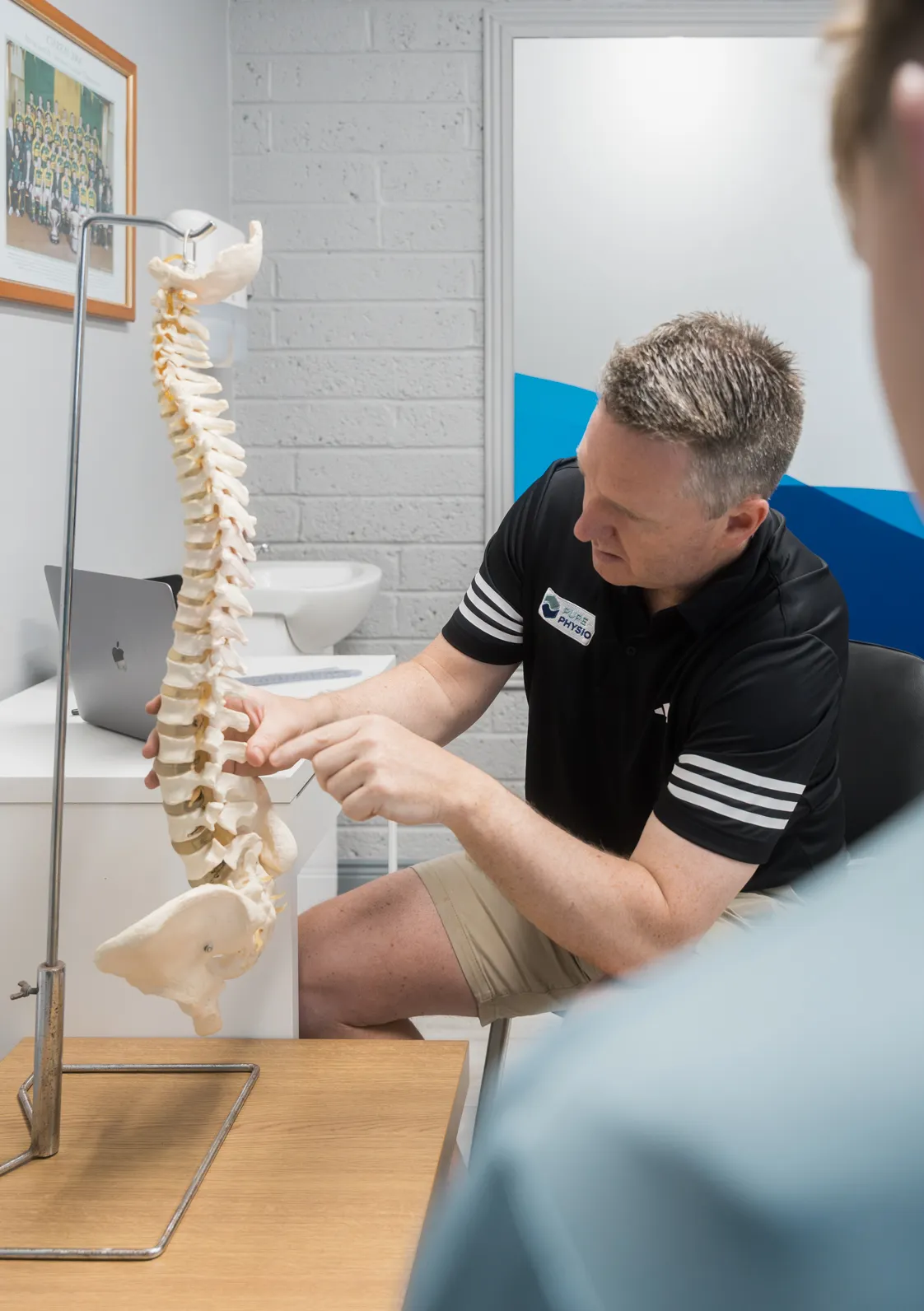 Physiotherapist pointing to the lower spine during an assessment