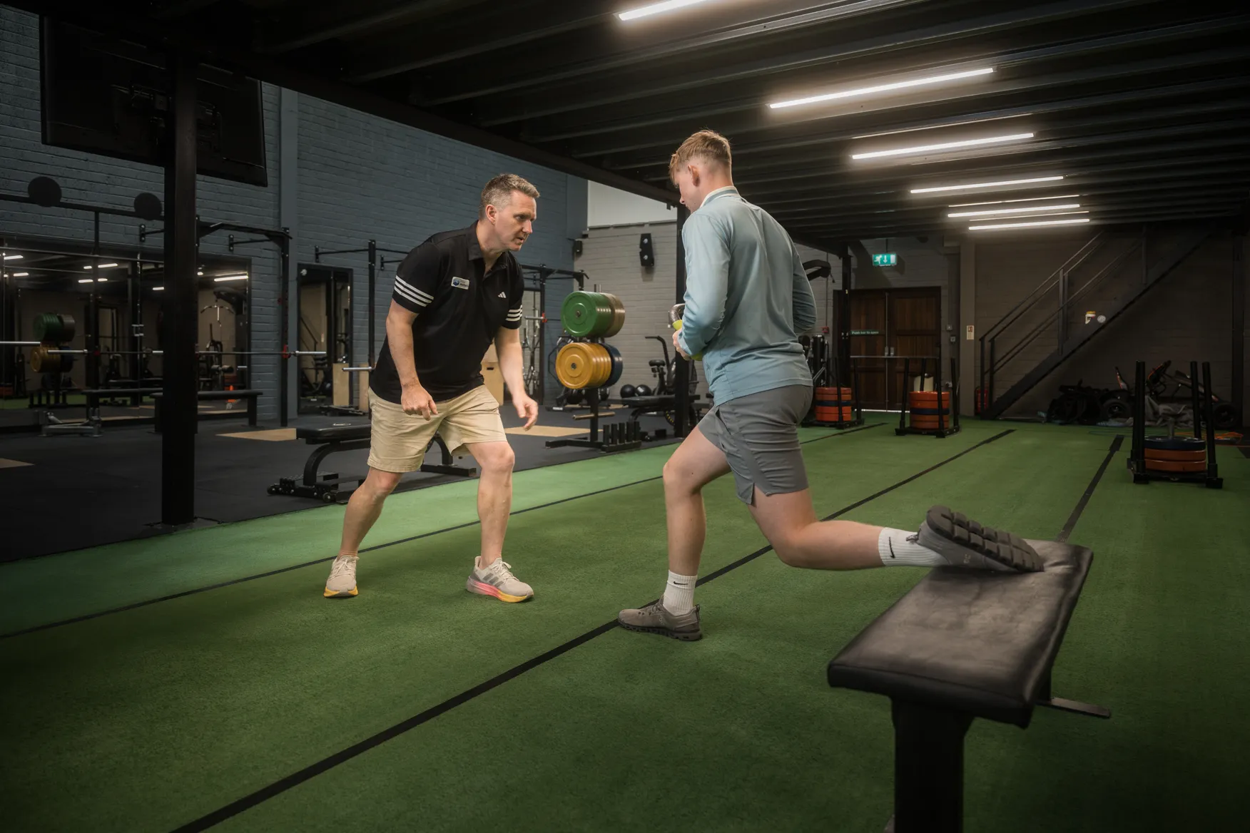 Physiotherapist coaching a split squat in the gym